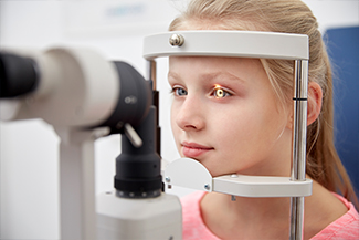 girl checking vision with tonometer at eye clinic