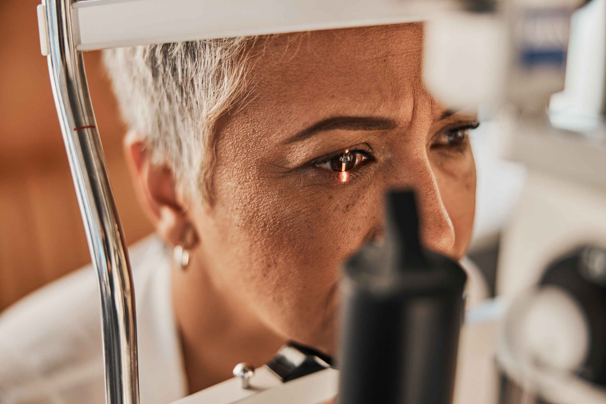 Laser, vision or senior customer in eye exam for eyesight at optometrist office in assessment or consultation. Face of mature woman testing or checking vision to help iris or retina visual health